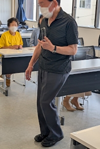 ビデオ通話をつないだスマートフォンを胸の前にかざし通話先の支援者がドア位置などの周辺状況を伝える様子