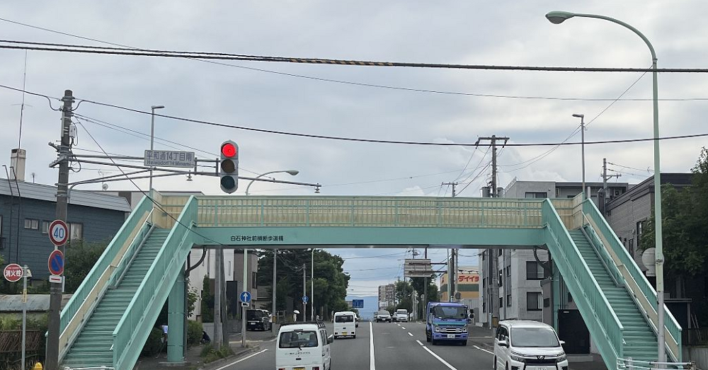 白石神社前横断歩道橋の画像。薄緑色の歩道橋に「白石神社前横断歩道橋」の文字が入っている。