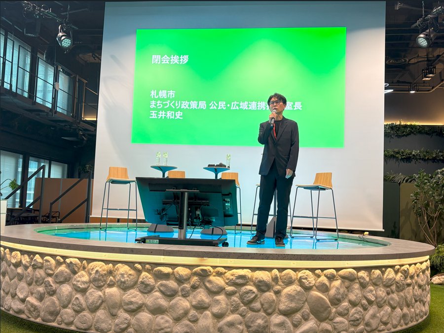 閉会挨拶で、ステージ上でマイクを持って話す玉井和史。